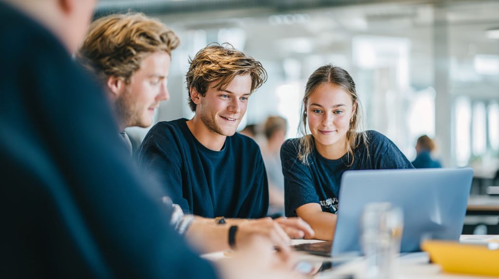 Vier junge Mitarbeitende arbeiten gemeinsam an einem Laptop.